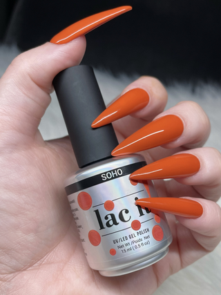 en Vogue Lac it! SoHo orange UV/LED gel polish for professional nails and extensions shown on stiletto nails holding polish bottle